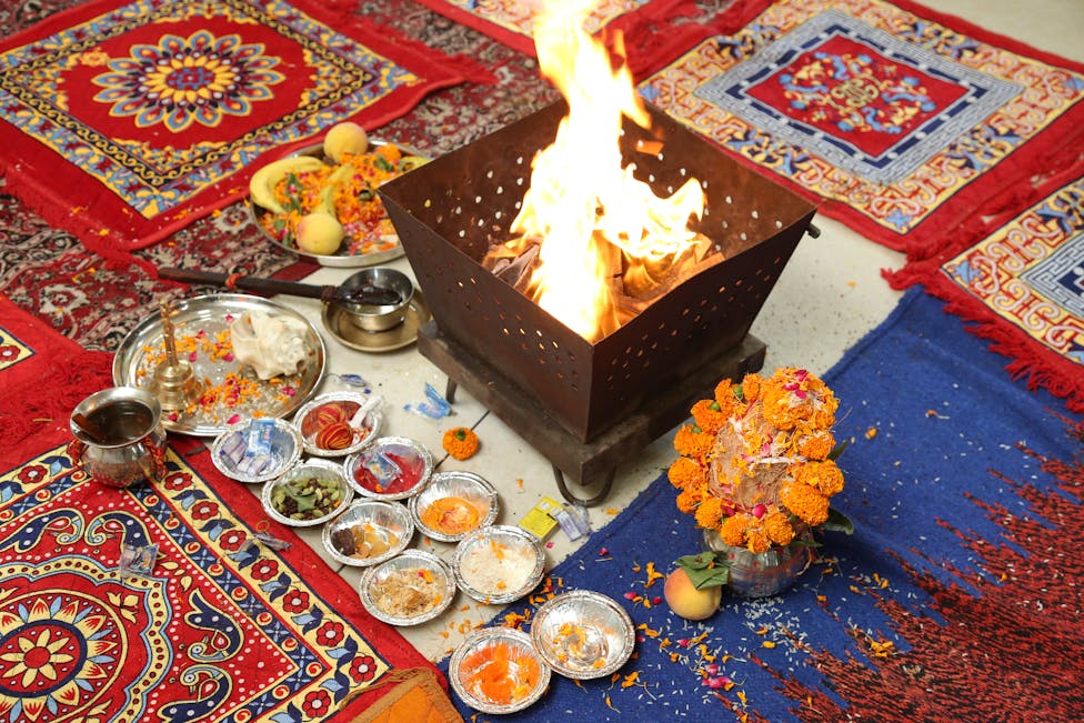 A fire ritual with vibrant offerings and patterned mats.